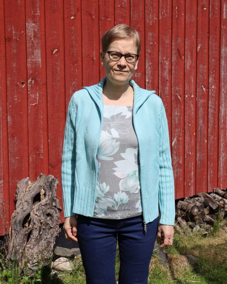 Woman standing in front of a barn wearing Liesl + Co Tribeca Knit Cami under a cardigan