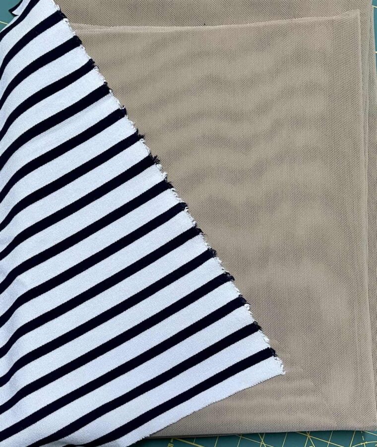 Flat lay of black and white striped fabric and tan nude power mesh fabric.