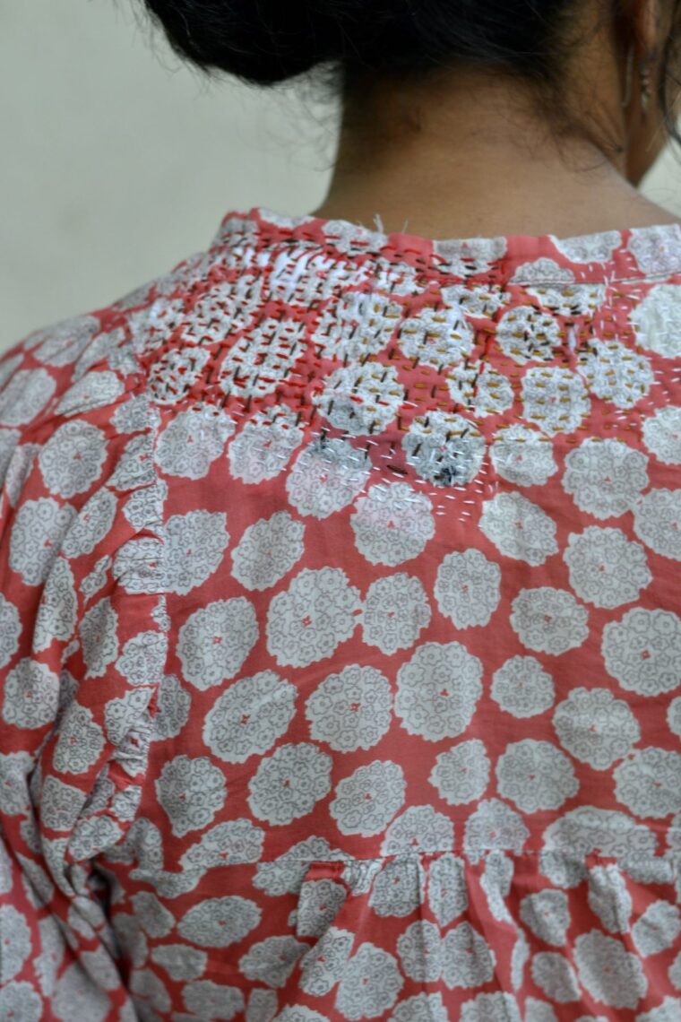 Woman wearing a shirt with visible mending on the back shoulder