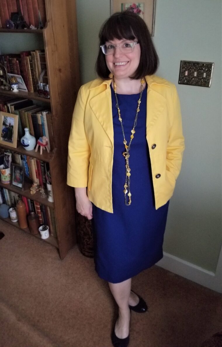 Woman wearing a blue Rush Hour dress with a yellow jacket