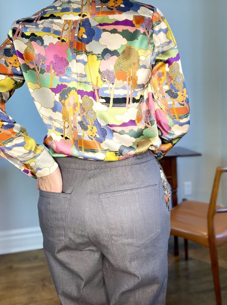 Back view of woman wearing grey trousers and a silk blouse