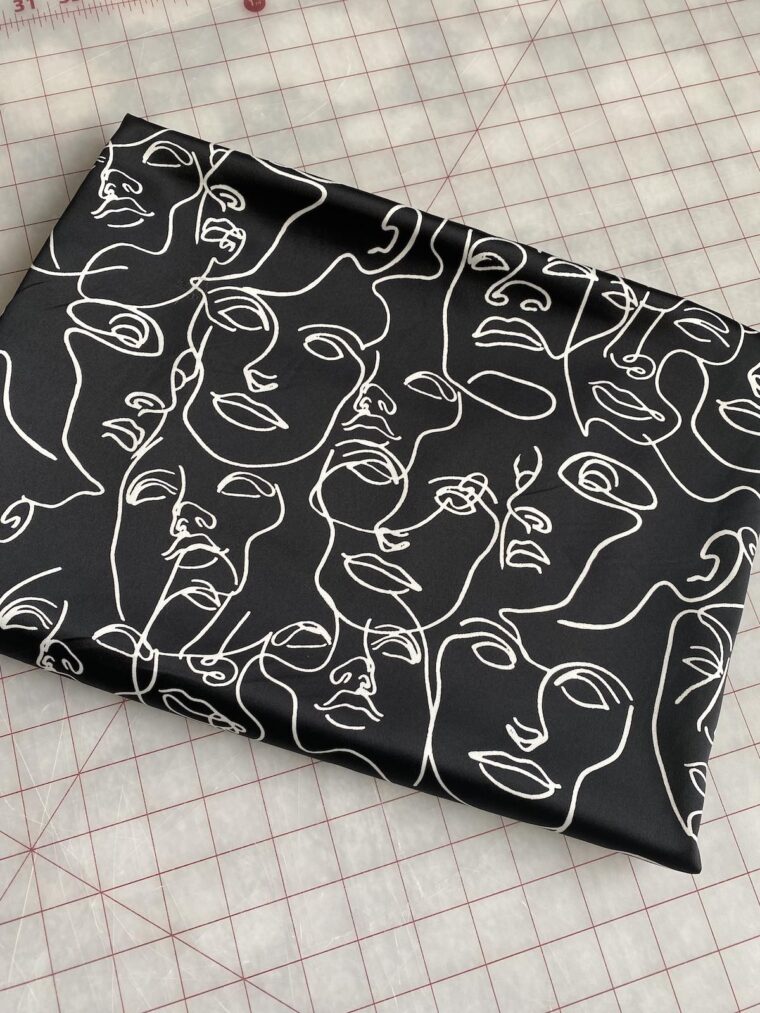 Close up of fabric with white faces printed on a black background