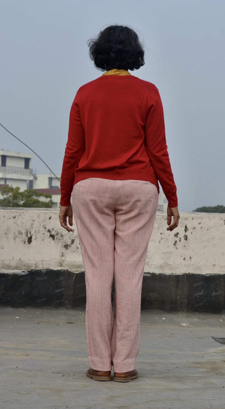 Back view of woman wearing red and white striped trousers and red sweater.