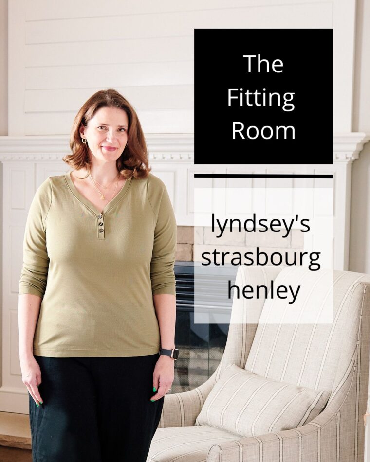 Woman wearing an olive henley standing in front of a fireplace. Text on the image says The Fitting Room: Lyndsey's Strasbourg Henley