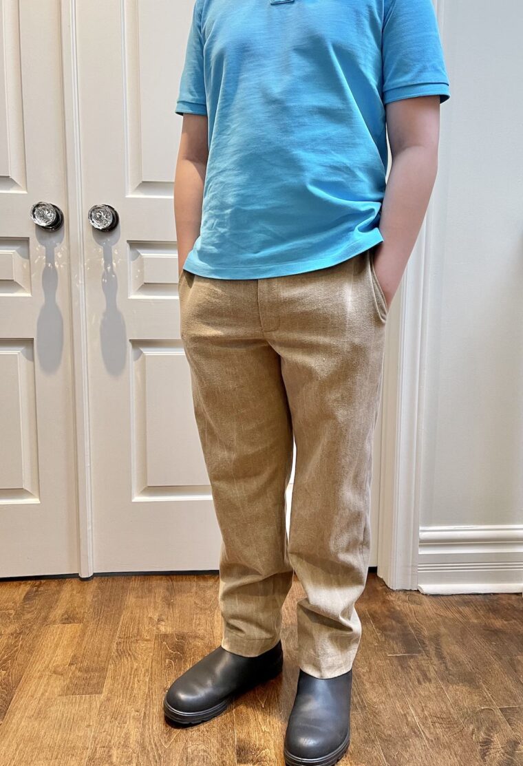 Young man wearing tan trousers and light blue polo top. Picture is from the shoulders down.