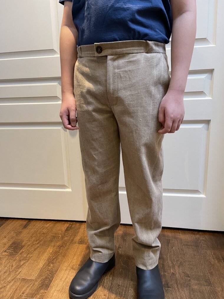 Young man wearing tan trousers and navy blue top. Picture is from the shoulders down.