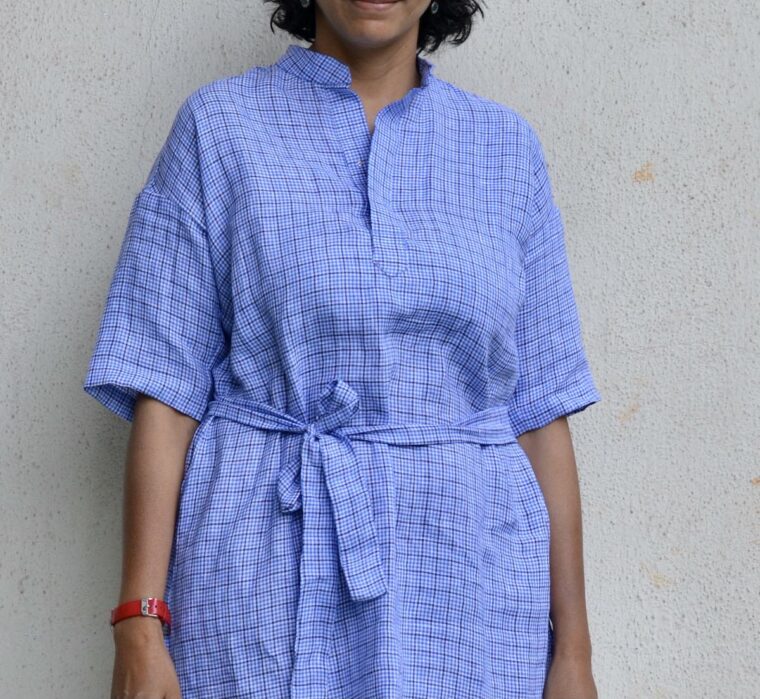 Woman wearing blue linen Santa Rosa Dress. The dress is belted The image is cropped up close.