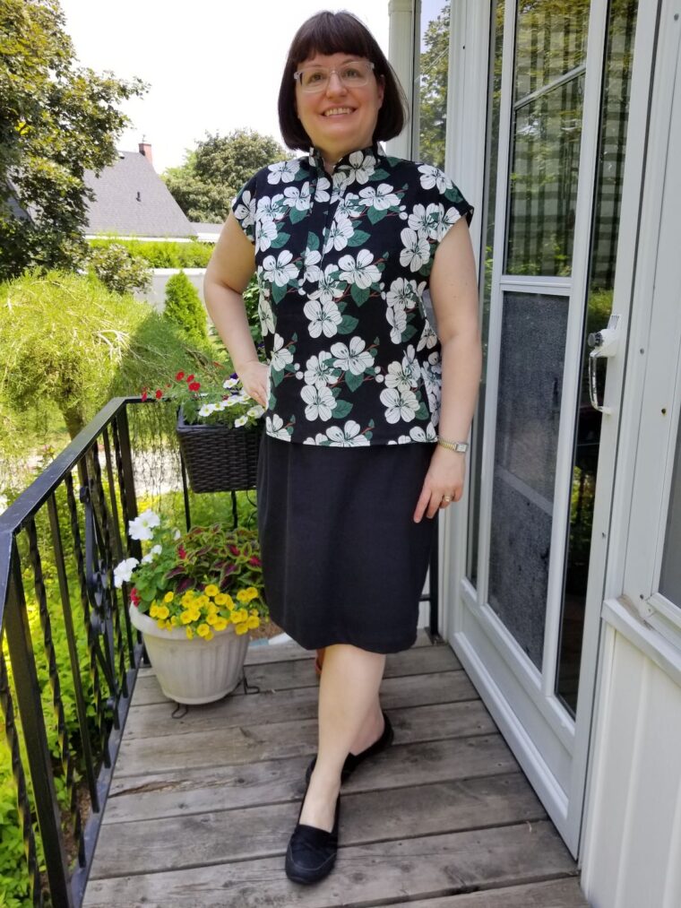 Smiling woman wearing a top made from a floral linen print. She has paired it with a straight black shirt.