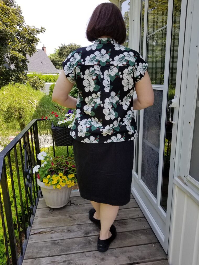Back view of a woman wearing a top made from a floral linen print. She has paired it with a straight black shirt.