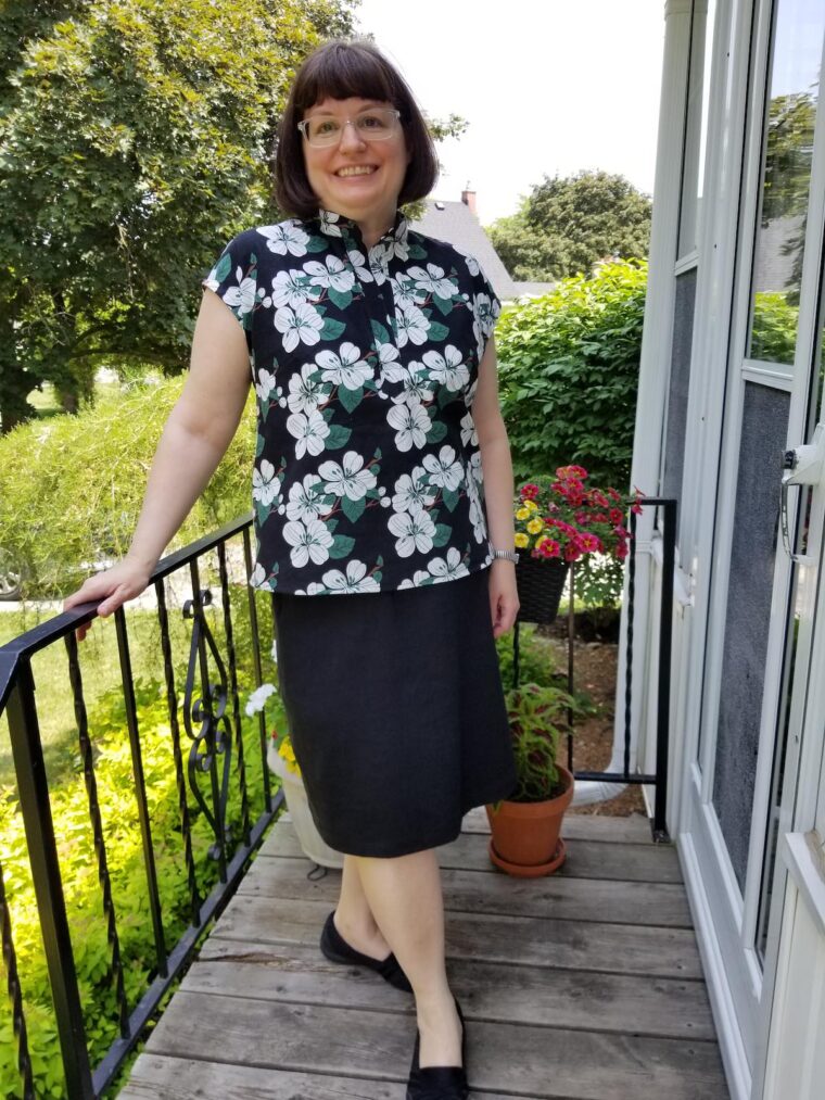 Smiling woman wearing a top made from a floral linen print. She has paired it with a straight black shirt.