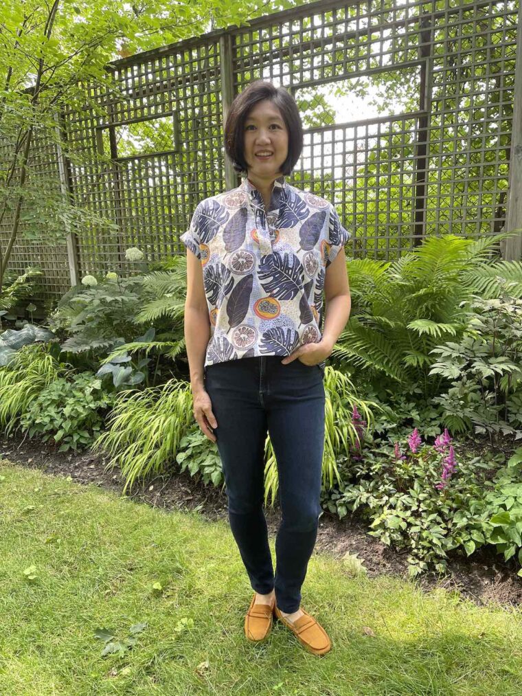 Woman standing in a backyard wearing a Santa Rosa top and jeans