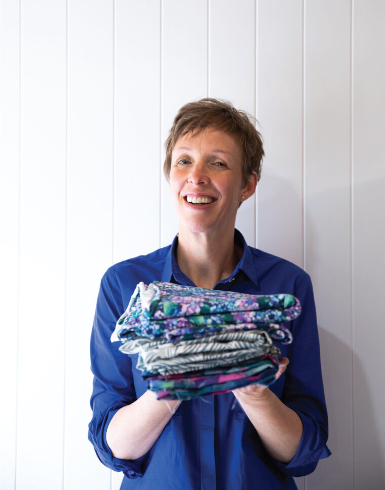Maaike with a stack of the fabrics she carries in her shop, Maaidesign